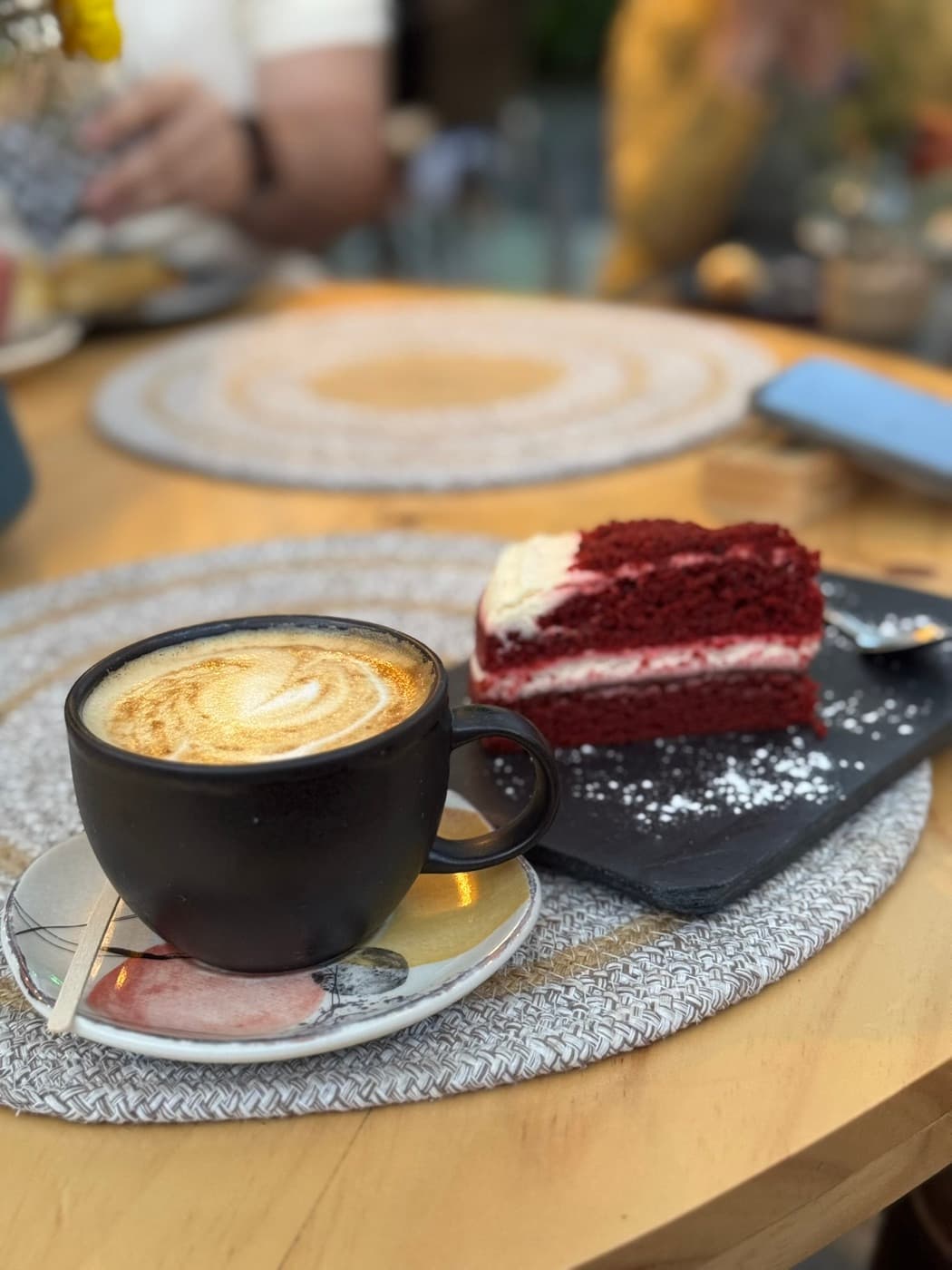 Capuchino con arte latte y porción de red velvet